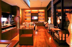 Un interior moderno con zona de bar, asientos y televisor.