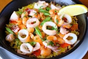 Un plat à base de fruits de mer et de riz, garni d’herbes et d’un quartier de citron.