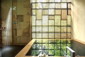 A bathroom with a wooden floor, a bathtub, and a shower.