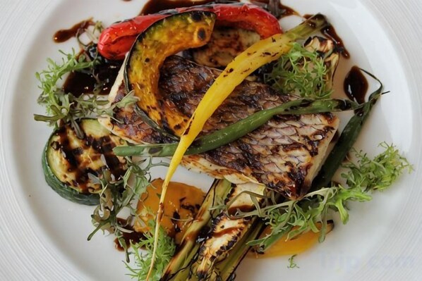 A plate of grilled fish with vegetables and sauce. - Sankara Hotel & Spa Yakushima (Yakushima)