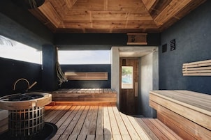 Un cuarto de sauna con bancos de madera, un banco con una toalla y una palangana para agua.