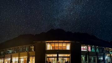 Un edificio con una amplia fachada de vidrio, una entrada destacada y un cielo nocturno estrellado.