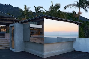 Un área de estar exterior moderna con vistas al océano y a las montañas.