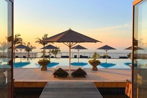 Un espace piscine équipé de parasols, de chaises longues et offrant une vue sur la mer.