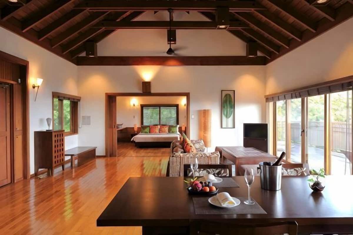 Une pièce spacieuse avec un plancher en bois, une table à manger avec des chaises, un canapé, un lit et une grande fenêtre.
