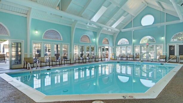 Una piscina interior con vistas despejadas al área de la piscina, rodeada de ventanas y asientos.