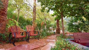 A garden with wooden benches, stone pathway, and lush greenery.