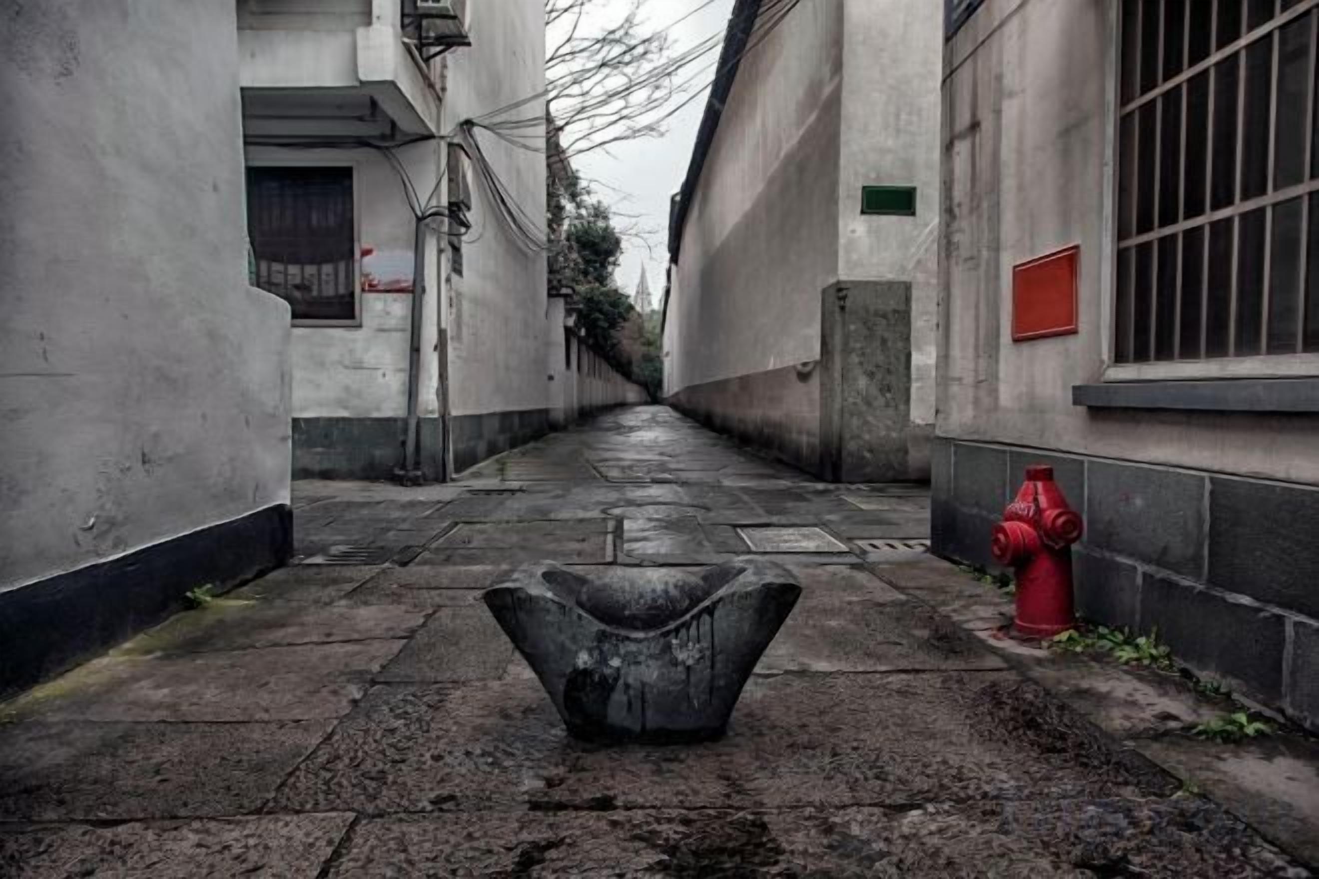 A narrow alleyway with a fire hydrant and a concrete basin in the foreground.