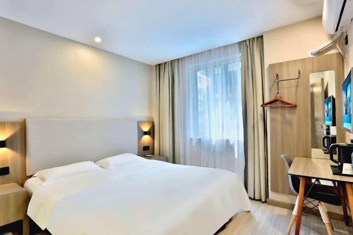 Ein Hotelzimmer mit einem großen Bett, einem Schreibtisch mit Stuhl, einem Spiegel und einem Garderobenschrank.