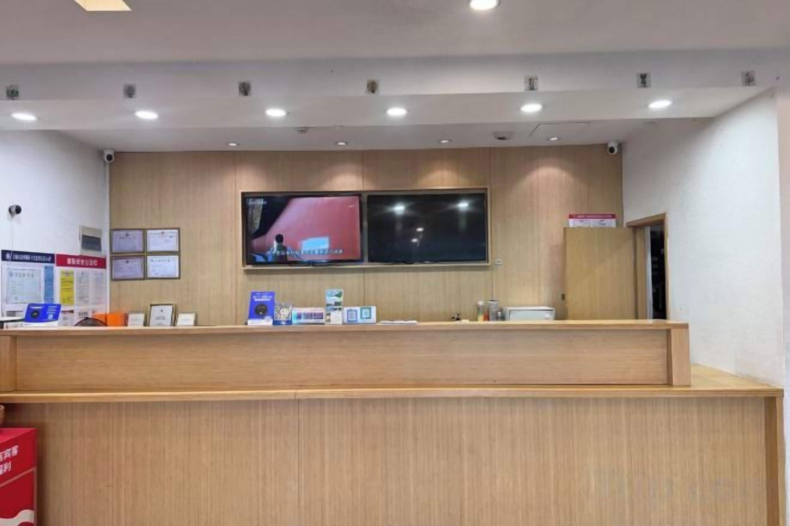 A reception desk with a flat-screen TV, a wooden counter, and a wall-mounted sign.