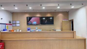 A reception desk with a flat-screen TV, a wooden counter, and a wall-mounted sign.