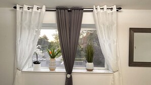 A window with a grey curtain, two white vases with plants, and a mirror on the wall. - Super Luxury House with 3 Bedrooms, 1-1/2 Washrooms, Basement and Free Parking (Toronto)
