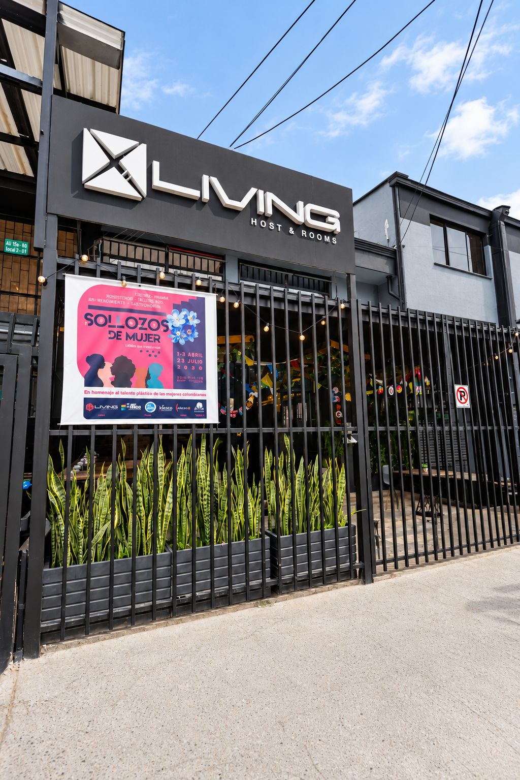Un edificio con un letrero que dice 'LIVING Host & Rooms' y un cartel grande anunciando el evento 'SOLOZOS DE MUJER'.