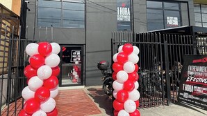 Un edificio con fachada negra y un logotipo rojo. Hay globos rojos y blancos en la entrada.