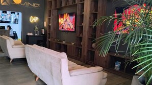 Ein modernes Wohnzimmer mit einer Couch, einem Fernseher, Holzregalen und Pendelleuchten.