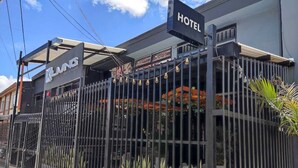 Un hotel con una cerca de metal, un letrero que indica que es un hotel y un cartel publicitario de 'XLING'.