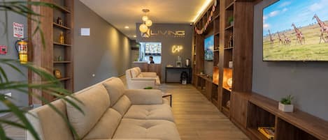 Una sala moderna con un sofá, estanterías de madera, un televisor y un letrero de neón.