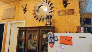 Una cocina con paredes de madera, un reloj grande y un refrigerador con imanes y notas.