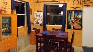 Un comedor con una mesa y sillas de madera, un aparador con puertas de cristal y una pared decorada con varios adornos, incluyendo un cuadro de un ciervo.
