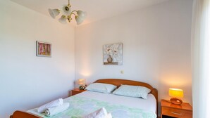 Ein Schlafzimmer mit einem hölzernen Bett, zwei Nachttischen mit Lampen, einer Deckenleuchte und zwei an der Wand befestigten Bildern.