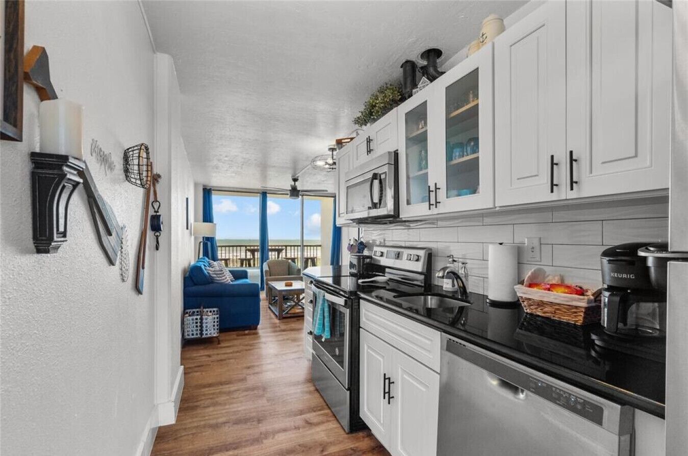 A modern kitchen with white cabinets, a black countertop, and a built-in oven.