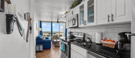 A modern kitchen with white cabinets, a black countertop, and a built-in oven.