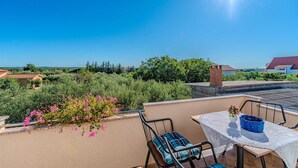 A rooftop terrace with a table and chairs, surrounded by greenery and a clear view of the landscape. - Emila's Apartment- Blue (Nin)