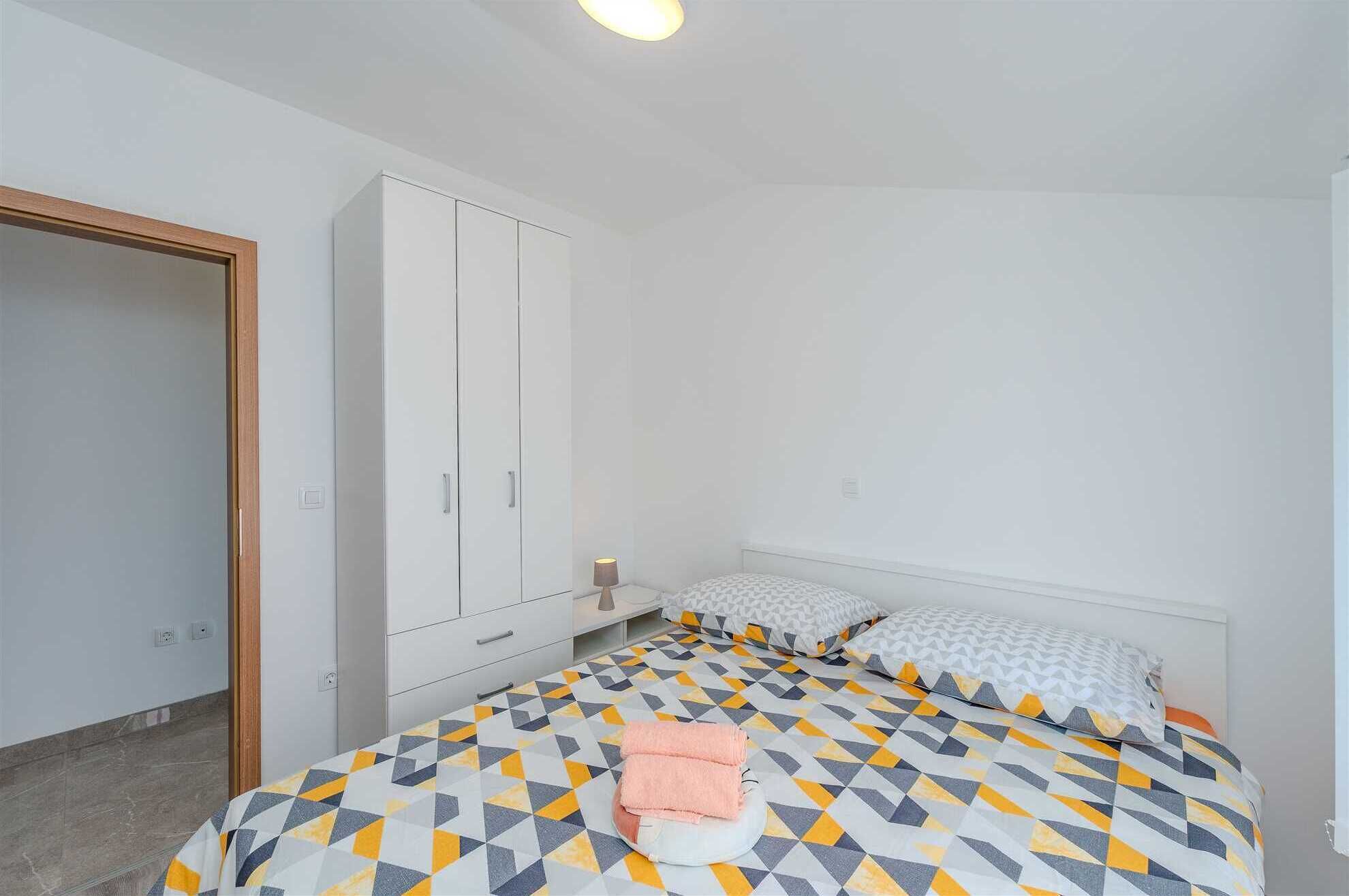 A bedroom with a bed, a wardrobe, and a bedside table.