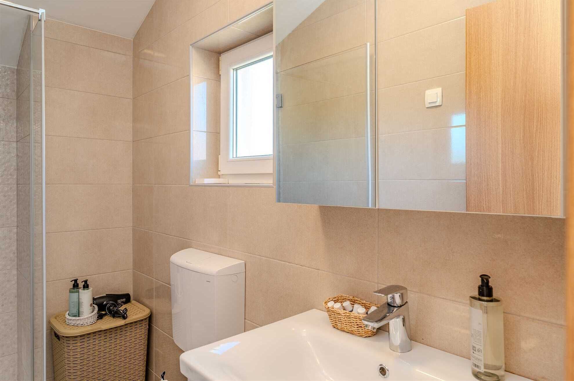 Ein Badezimmer mit Waschbecken, Spiegel, Toilette und Duschbereich.