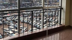 A room with a large window overlooking a busy parking lot and a cityscape. - ROYAL COMPLEX HOTEL AND APARTMENTS (Kampala)