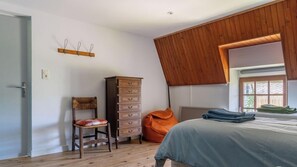 Quarto com teto de madeira, cama, cômoda, cadeira e janela.