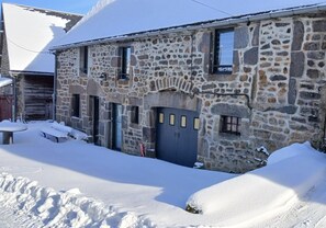 Um edifício de pedra com telhado coberto de neve e um pequeno alpendre.
