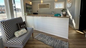 A modern kitchen with a central island, pendant lighting, and a view of the outside. - The Lamplight Inn (Lavallette)