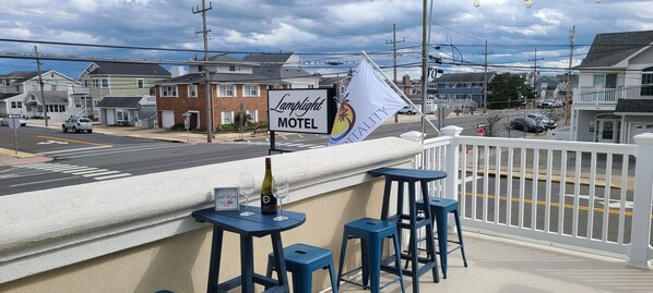 A motel with a signboard, outdoor seating with stools, and a view of the street.