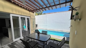 A patio with a glass table and chairs, a pool, and a covered area with a ceiling fan. - Casa Sueños in Bucerias Mexico with Private Pool and Private Parking Garage.  (Bucerías)