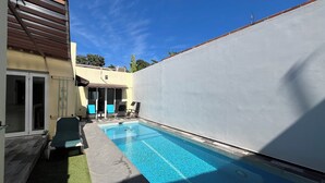 A swimming pool with a tiled deck, a covered seating area, and a white wall. - Casa Sueños in Bucerias Mexico with Private Pool and Private Parking Garage.  (Bucerías)