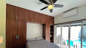 A bedroom with a bed, wooden wardrobe, ceiling fan, and a view of a swimming pool through a glass door. - Casa Sueños in Bucerias Mexico with Private Pool and Private Parking Garage.  (Bucerías)