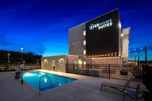A hotel named 'EVERHOME SUITES' with a swimming pool, outdoor seating, and a stone facade. - Everhome Suites Fayetteville near Fort Bragg (Fayetteville)