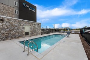 Zona de piscina con un edificio de fachada de piedra al fondo, identificado con el rótulo 'EVERHOME SUITES'.