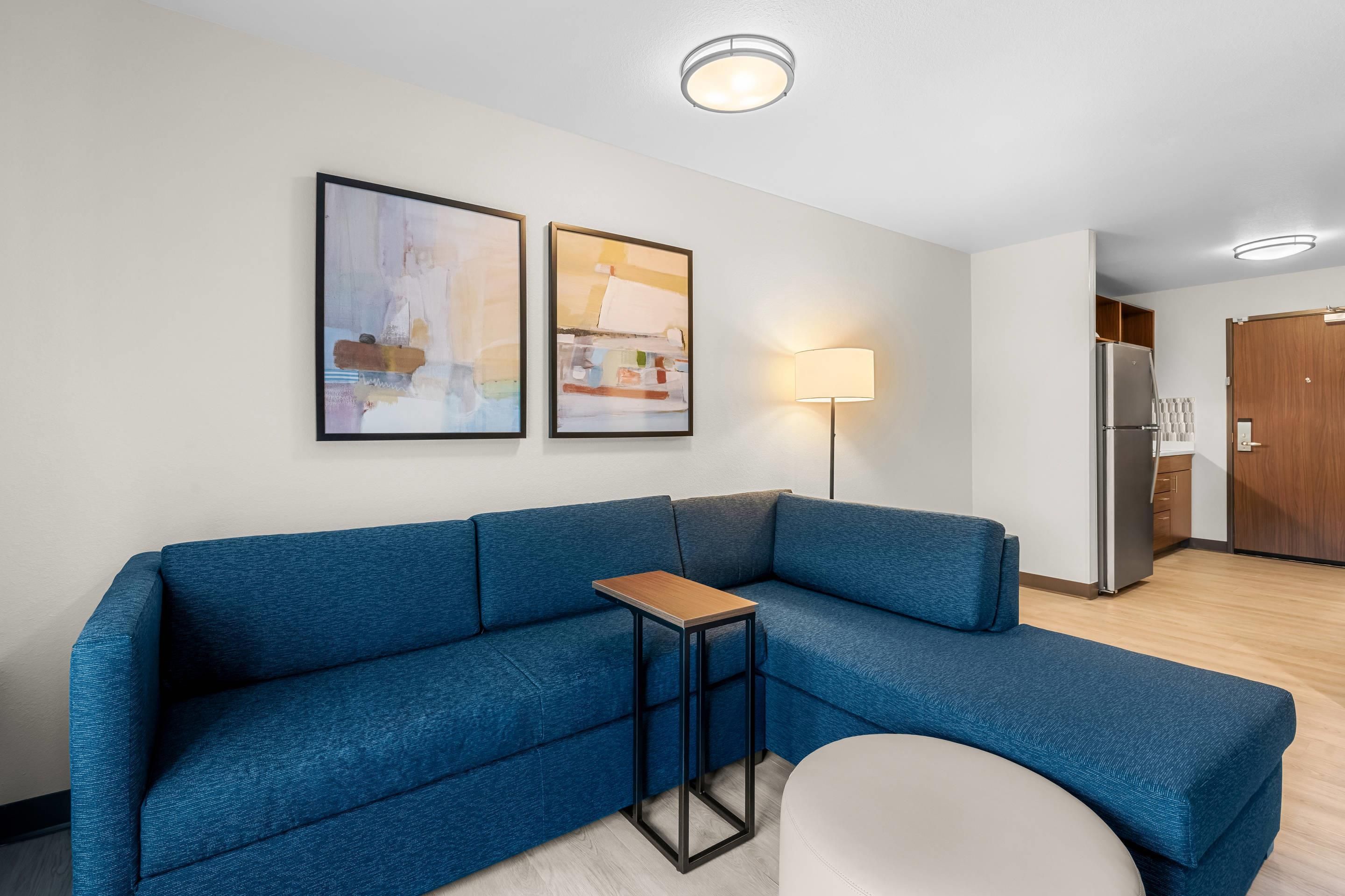 Un salon moderne avec un canapé bleu, une petite table et deux tableaux abstraits accrochés au mur.