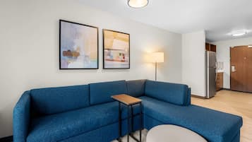 Una sala de estar moderna con un sofá azul, una mesita y dos cuadros abstractos en la pared.