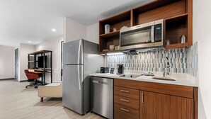 Una cocina moderna con electrodomésticos de acero inoxidable, armarios de madera y salpicadero de azulejos.