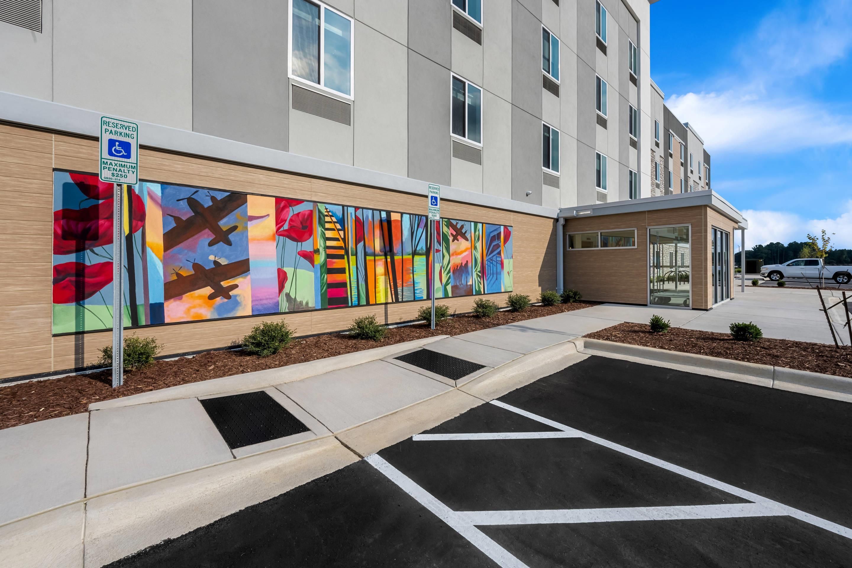 A modern building with a parking area and a colorful mural on the wall.