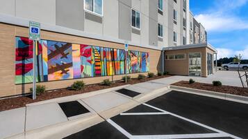 A modern building with a parking area and a colorful mural on the wall.