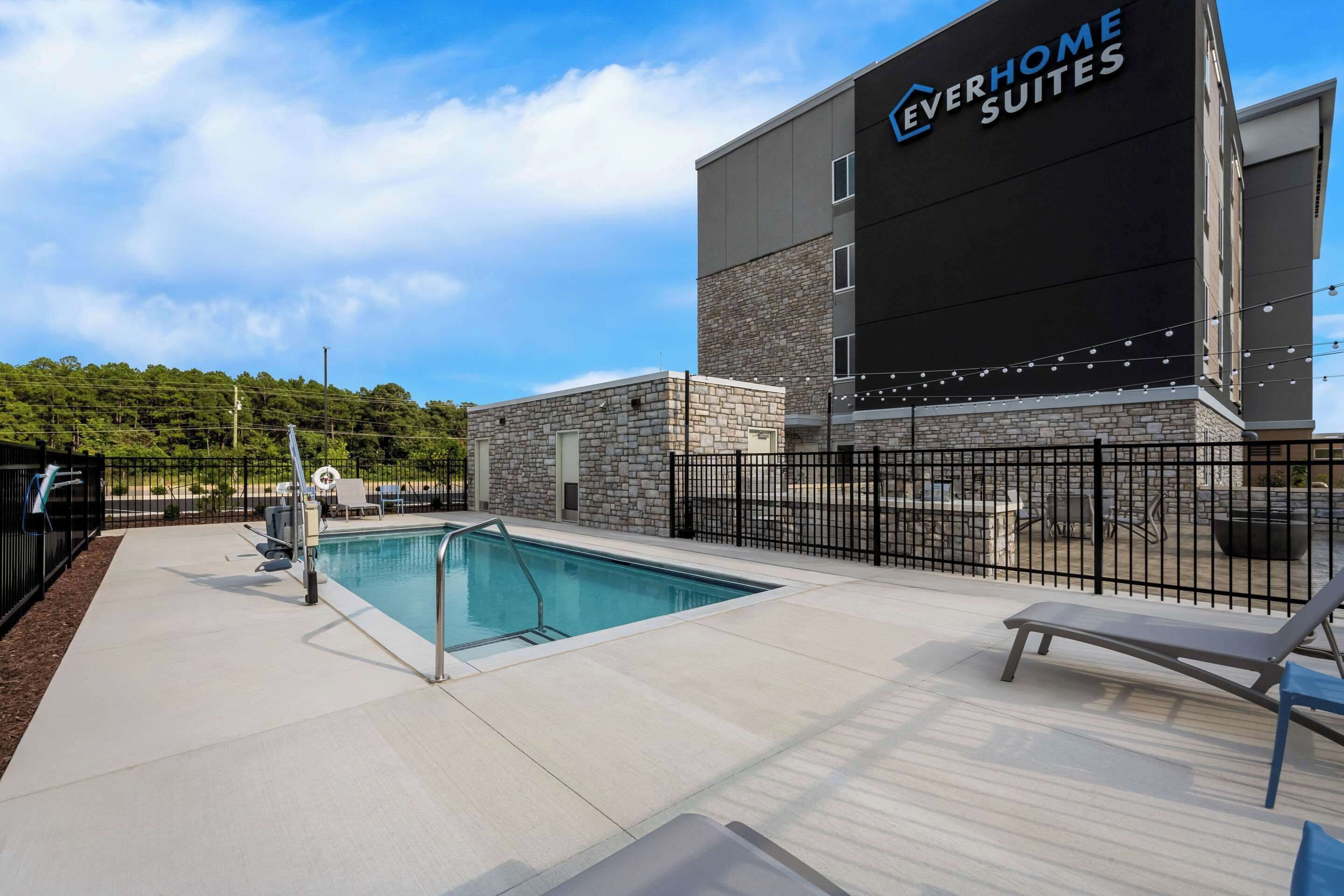 Un área de piscina con sillones de descanso y un edificio que dice "Everhome Suites".