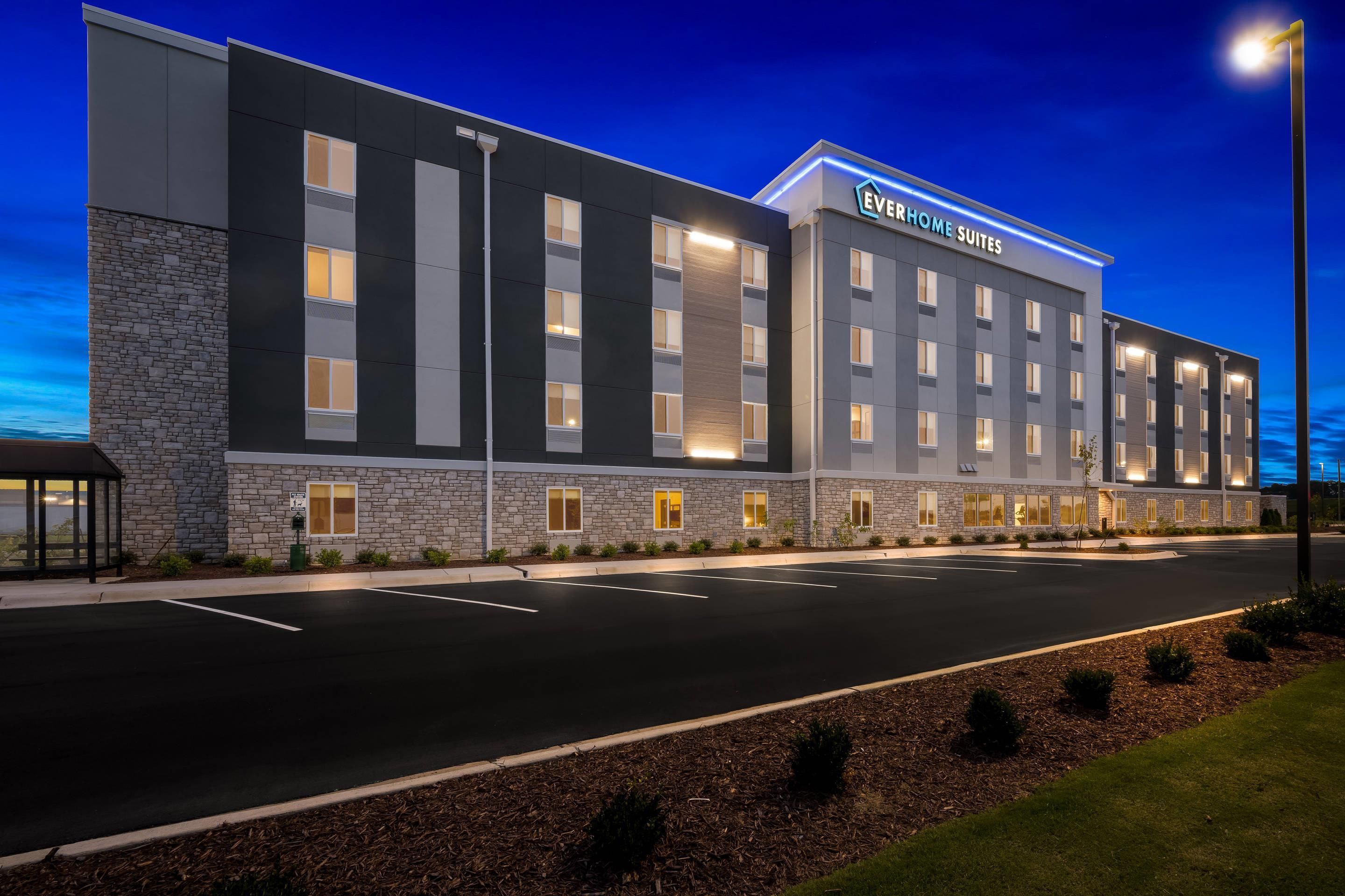 A modern hotel building with a flat roof, multiple windows, and a sign reading 'EverHome Suites.'