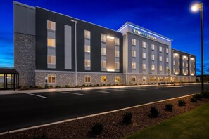 Un moderno edificio de hotel con techo plano, múltiples ventanas y un letrero que dice 'EverHome Suites'.