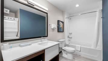 Une salle de bain moderne avec un grand miroir, un lavabo, des toilettes et une baignoire.
