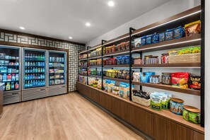 A grocery store interior with refrigerated beverage dispensers, shelves stocked with snacks, and packaged goods. - Everhome Suites Fayetteville near Fort Bragg (Fayetteville)