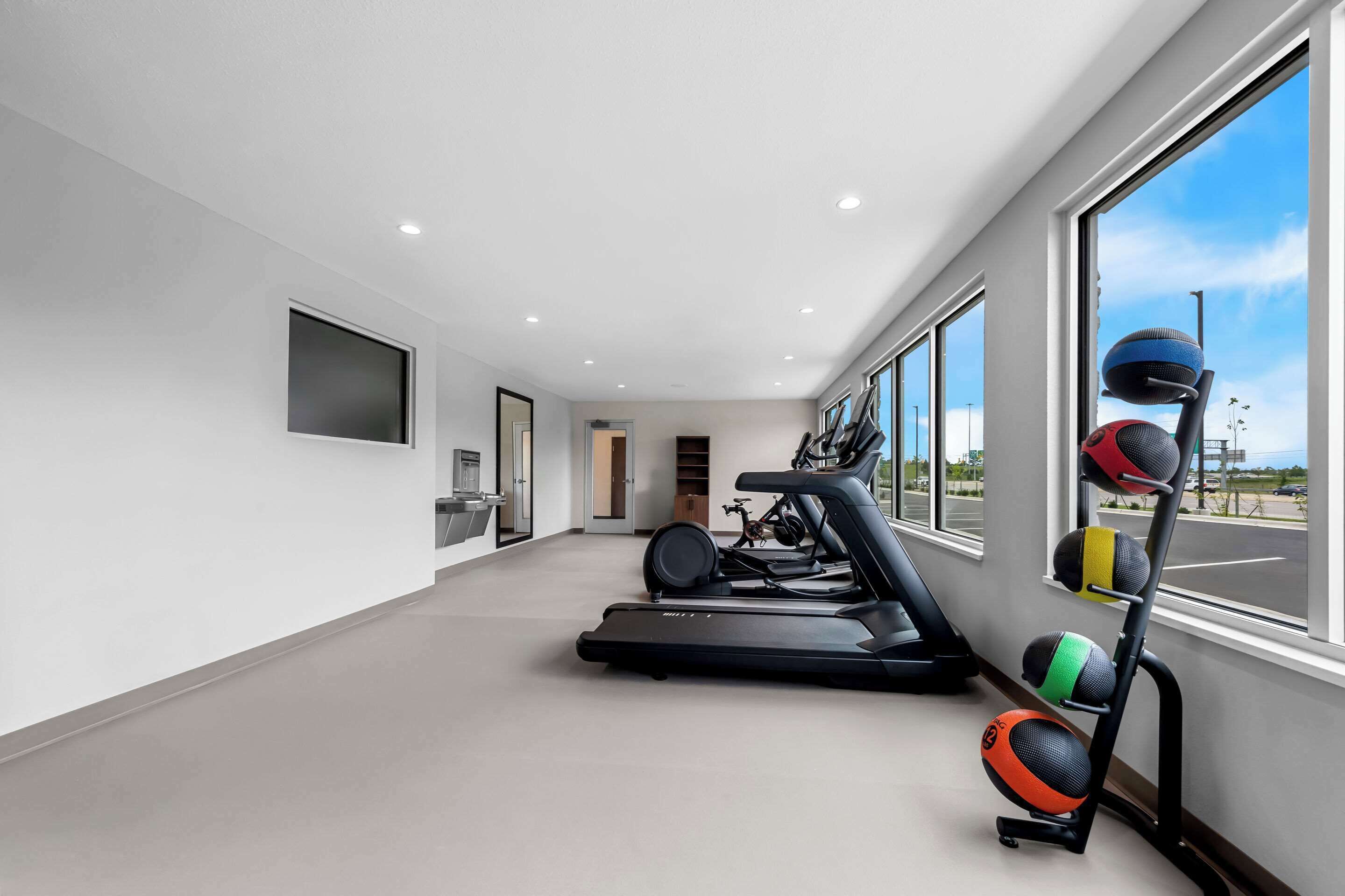 Une salle de sport à domicile équipée de tapis de course, d'un vélo d'appartement et d'un porte-balles d'exercice.